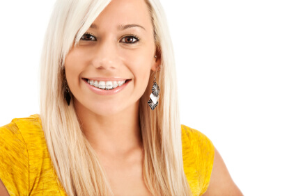 An adult woman with braces smiles.