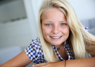 A young girl smiles, showing off her braces.