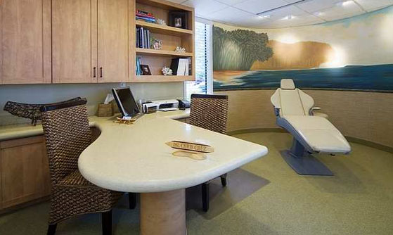 An exam room at Cruz Orthodontics. The room features a desk and an exam chair with beach decor.